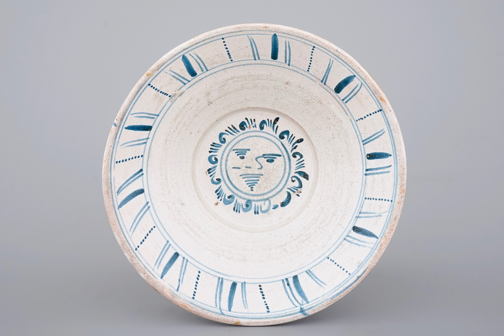 A large Spanish blue and white faience bowl with a sun face, 19th C.